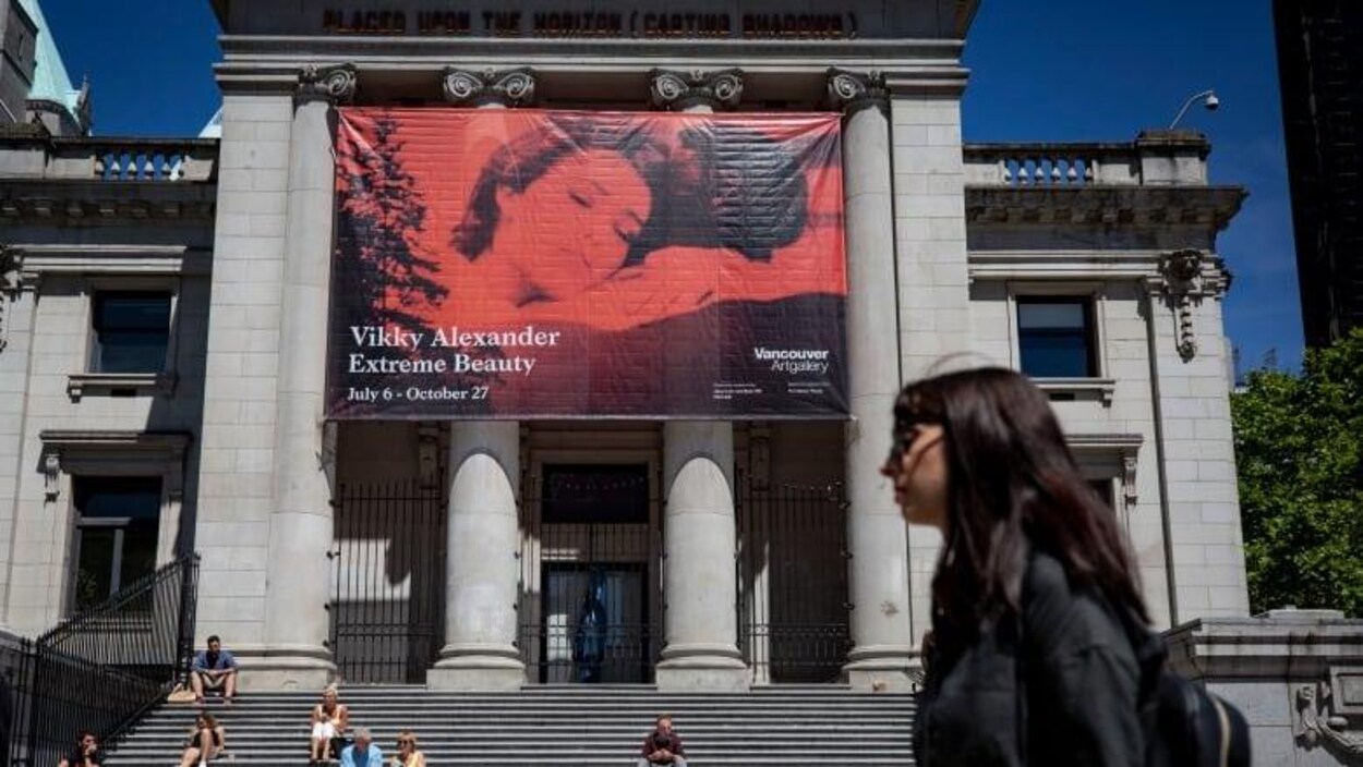 Une femme marche devant le musée des beaux-arts de Vancouver.