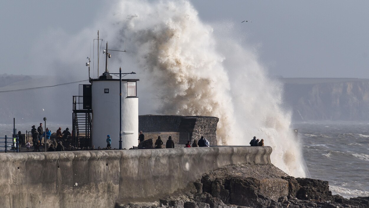 Une vague frappe un quai avec force, soulevant un nuage d'écume.