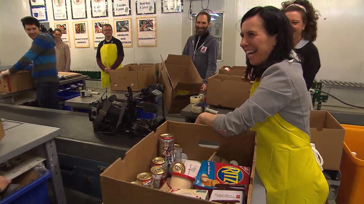 Valérie Plante, qui porte un tablier jaune, remplit une boîte de nourriture. Valérie Plante, qui porte un tablier jaune, remplit une boîte de nourriture.