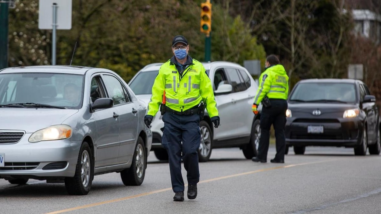 Un policier de Vancouver porte un masque et dirige la circulation.