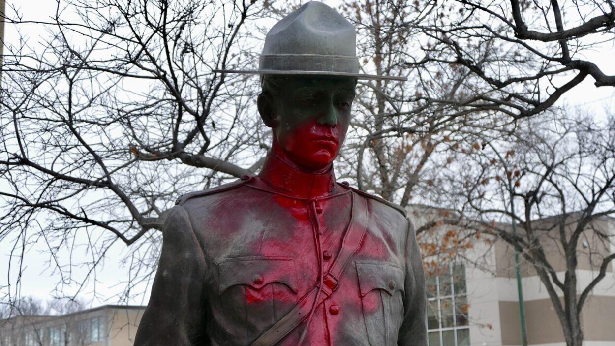 Une statue d'un agent de la GRC en bronze recouverte d'un graffiti rouge.