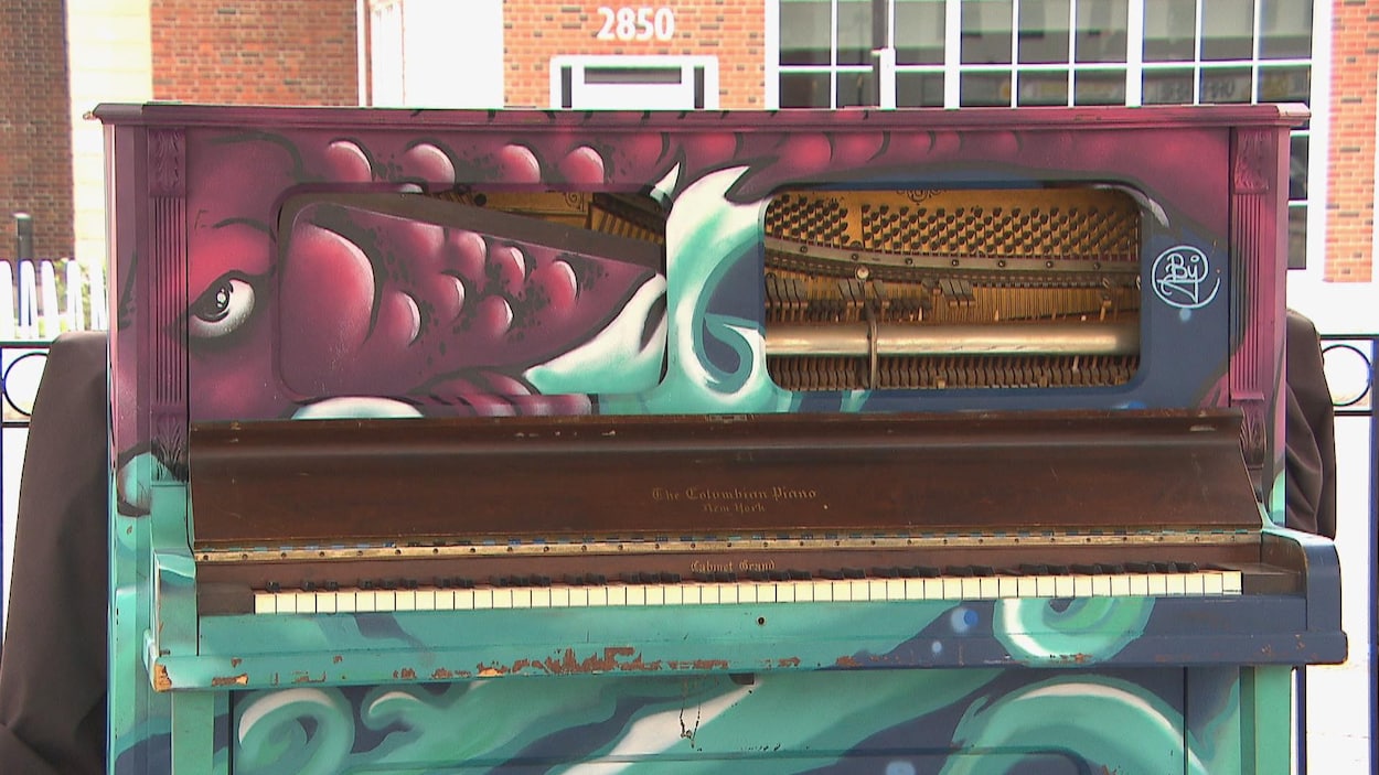 Un piano endommagé se trouve devant une bâtisse.