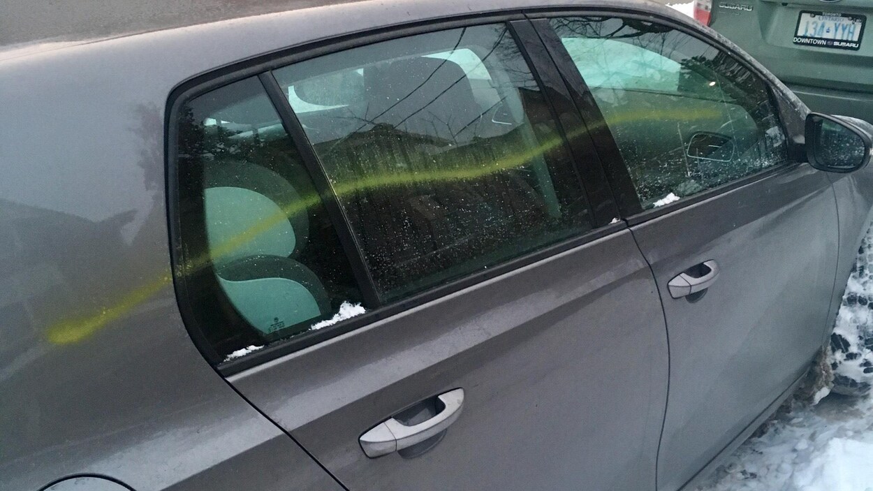 Photo montrant une ligne de peinture jaune sur toute la longueur des vitres d'un côté d'une voiture grise. Photo montrant une ligne de peinture jaune sur toute la longueur des vitres d'un côté d'une voiture grise.