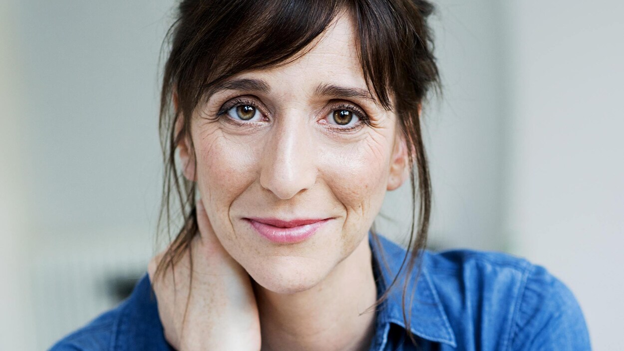 Portrait en couleur de l'autrice Vanessa Seiler, sur fond gris pâle. Elle porte une chemise bleue en denim.