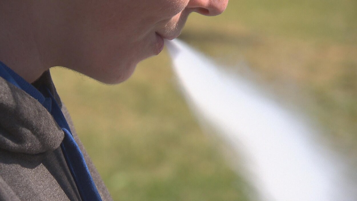 Un adolescent expire une épaisse fumée provenant d'une cigarette électronique qu'il vient de respirer. 