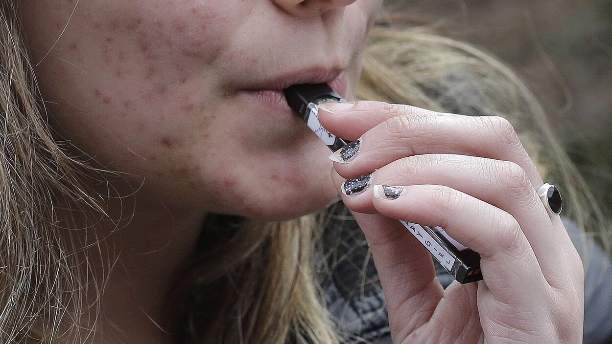 Une jeune femme qui fume une cigarette électronique.
