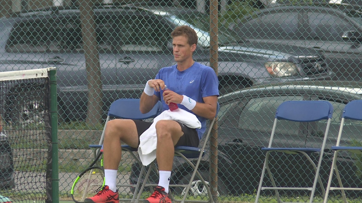 Il est assis sur une chaise au bord d'un terrain de tennis.