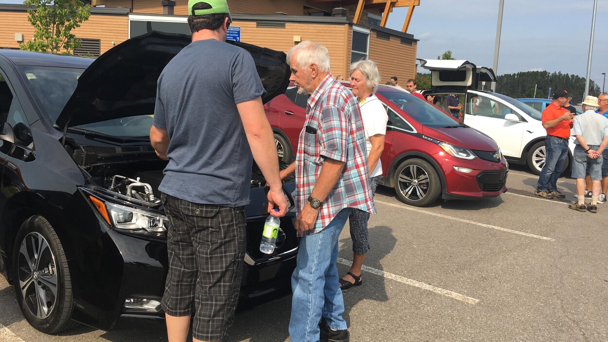Des gens qui regardent sous le capot d'une voiture Des gens qui regardent sous le capot d'une voiture