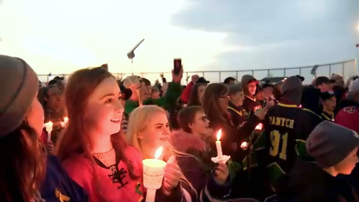 Des jeunes rassemblés dehors tiennent dans leurs mains des bougies lors de la veillée aux chandelles à Airdrie en Alberta