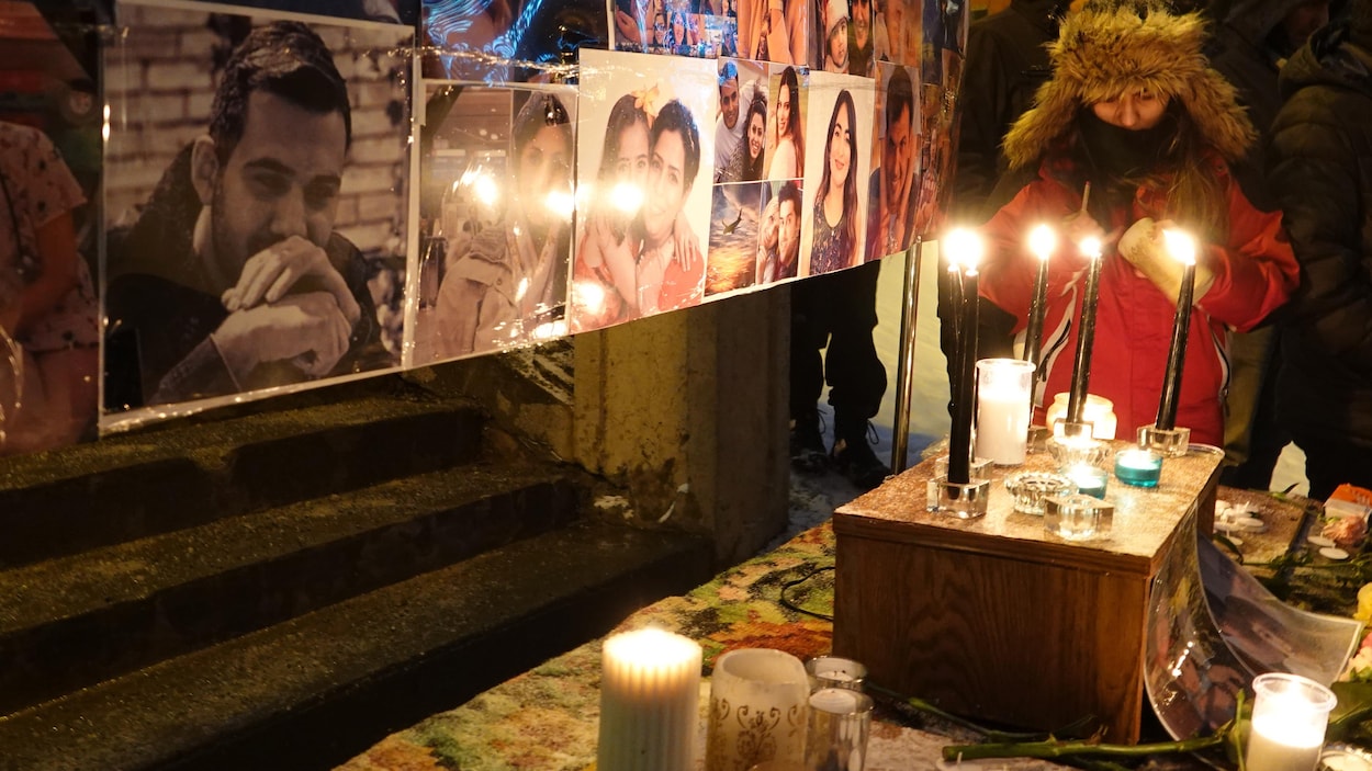 Une personne allume une bougie devant des photos des victimes canadiennes de l'écrasement.