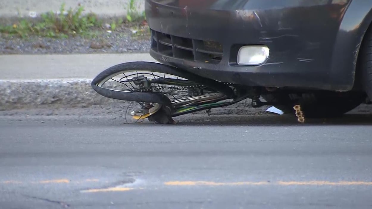 Le vélo est écrasé sous le devant de la voiture.