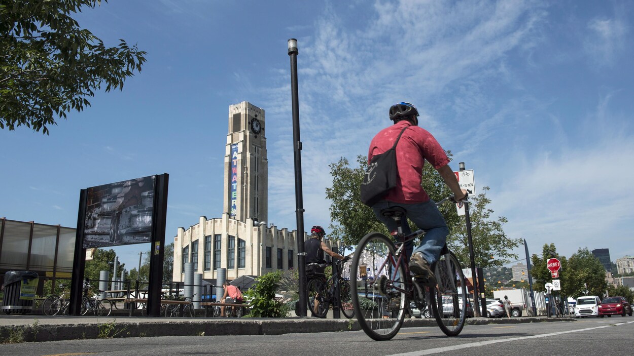 Un cycliste passe près du marché Atwater, par une belle journée d'été.