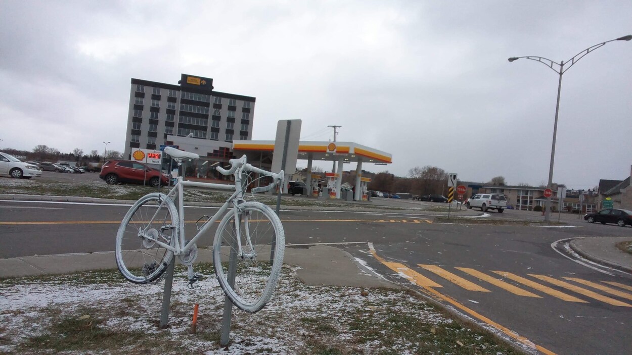 Un vélo peinturé et accroché sur un terre-plein.