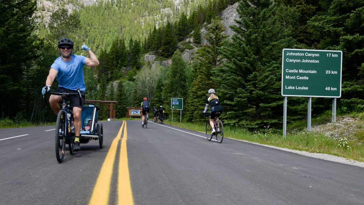 Un cycliste heureux de rouler sur une route sans voitures lève le poing dans les airs.