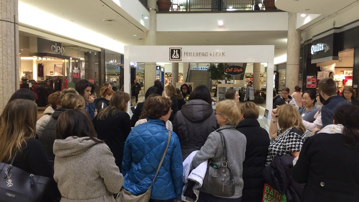 Plusieurs personnes font la queue dans un centre commercial