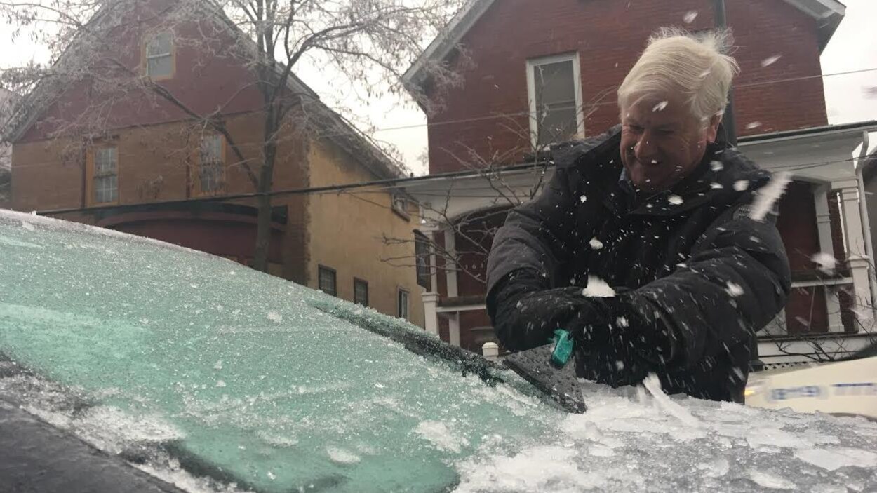 Un homme racle le pare-brise de sa voiture à Ottawa. Un homme racle le pare-brise de sa voiture à Ottawa.