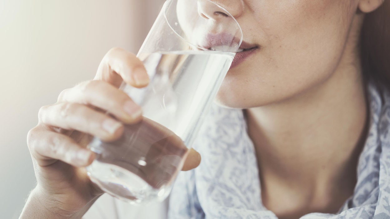 Une femme boit un verre d'eau.