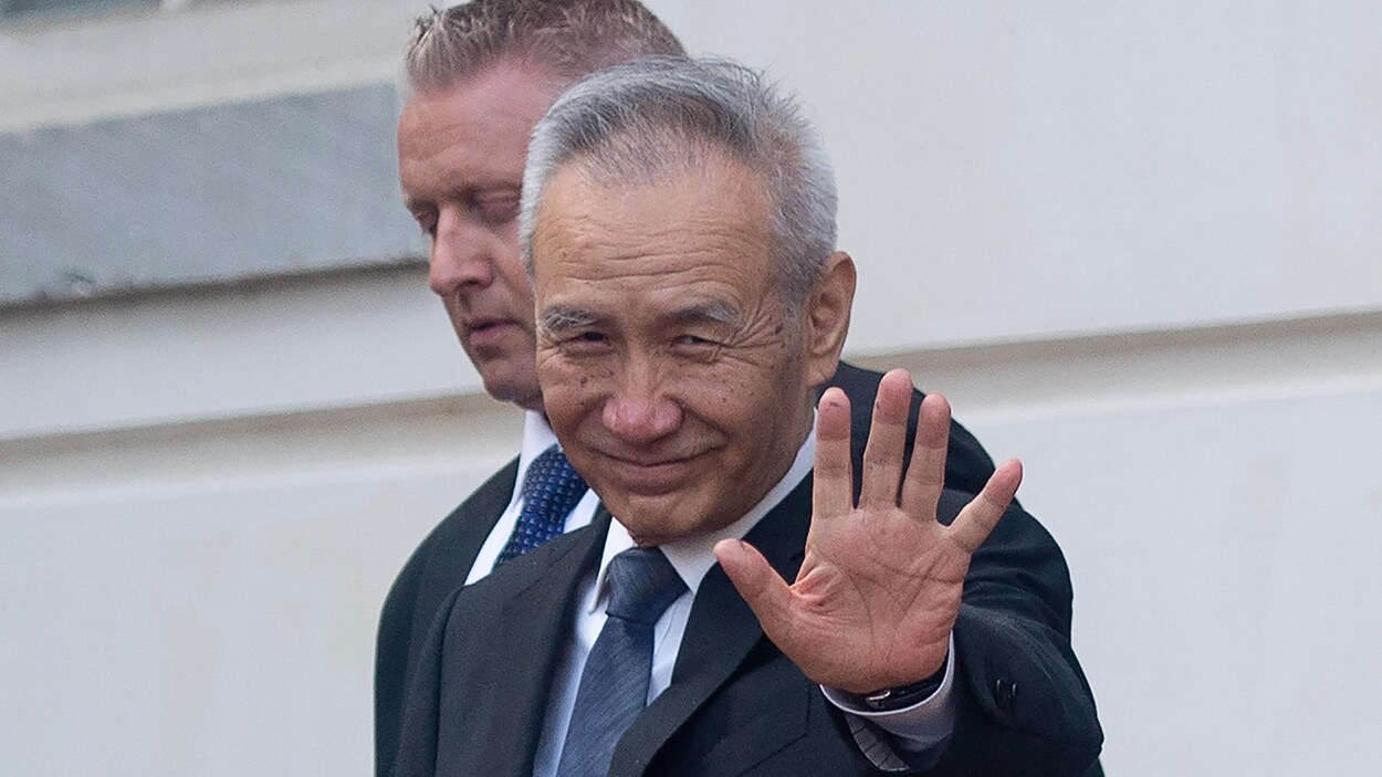 Le vice-premier ministre chinois, Liu He, saluant la caméra, alors qu'il est accompagné d'un autre homme, les deux portant un complet-cravate.