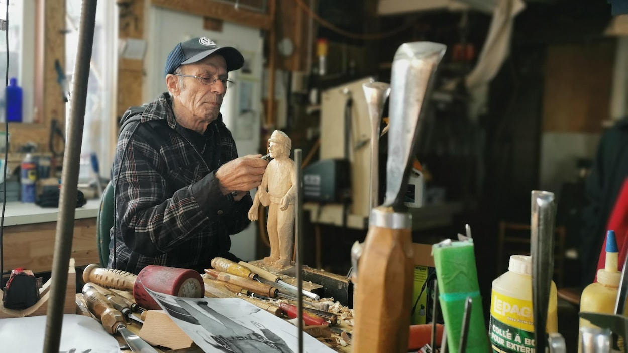 L'artiste Victor Dallaire sculpte un personnage en bois dans son atelier.