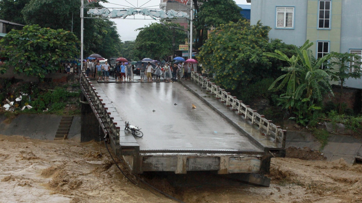 Des résidents regardent un pont qui a été brisé par la crue des eaux. Des résidents regardent un pont qui a été brisé par la crue des eaux.