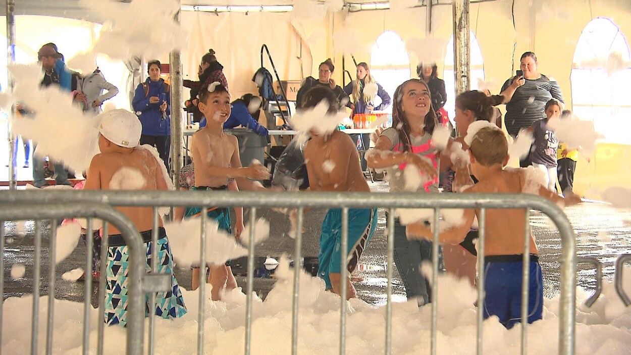 Des jeunes jouent dans la mousse sous un chapiteau.