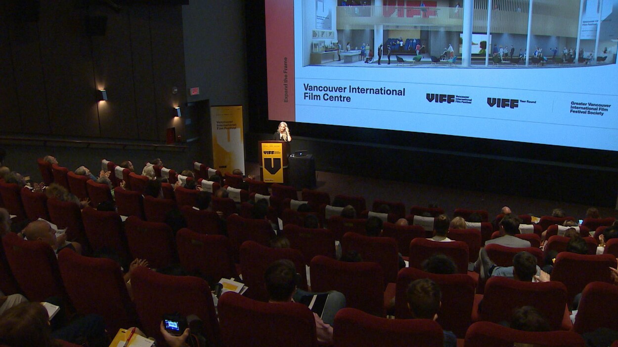 une femme au podium devant des spectateurs dans une salle de cinéma