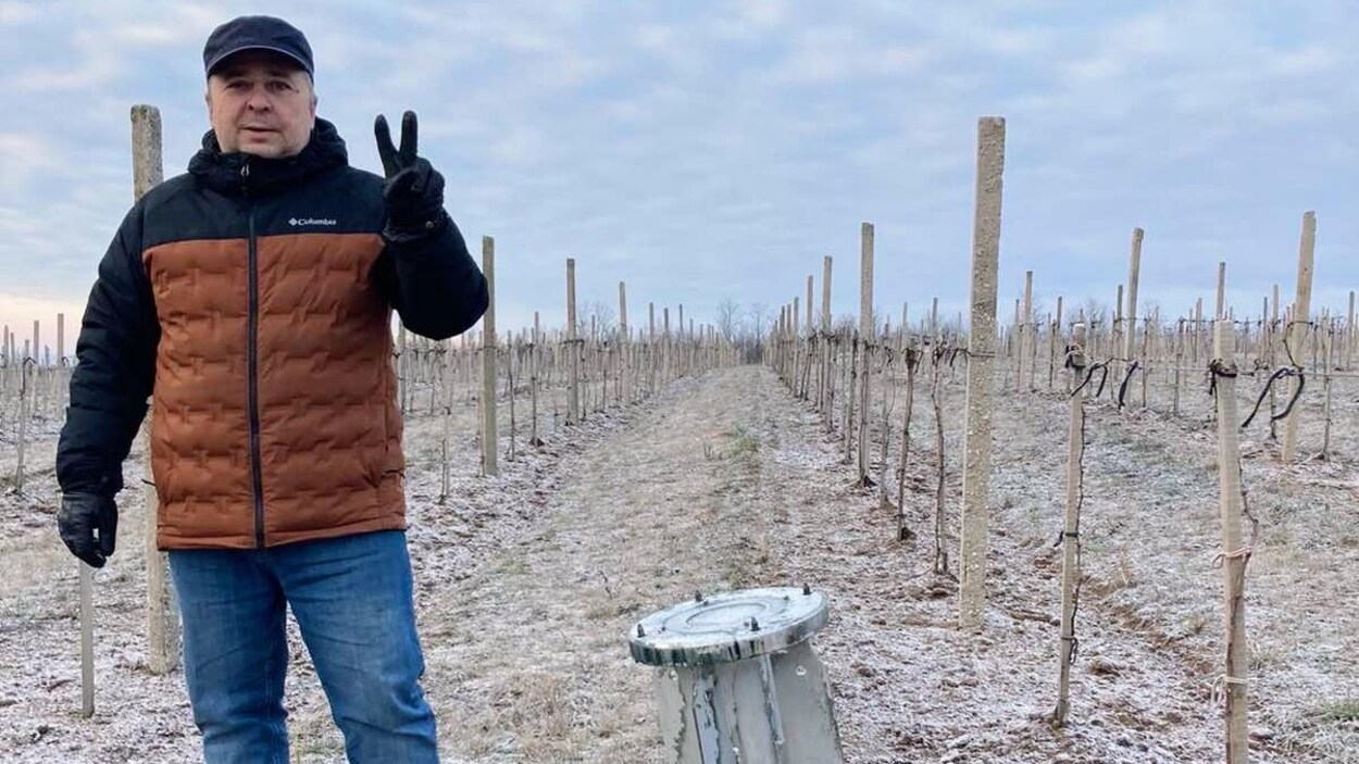 Mykhailo Molchanov, le mari de Svitlana Molchanova, fait un signe de paix à côté d'une roquette plantée dans le sol du vignoble Slivino.