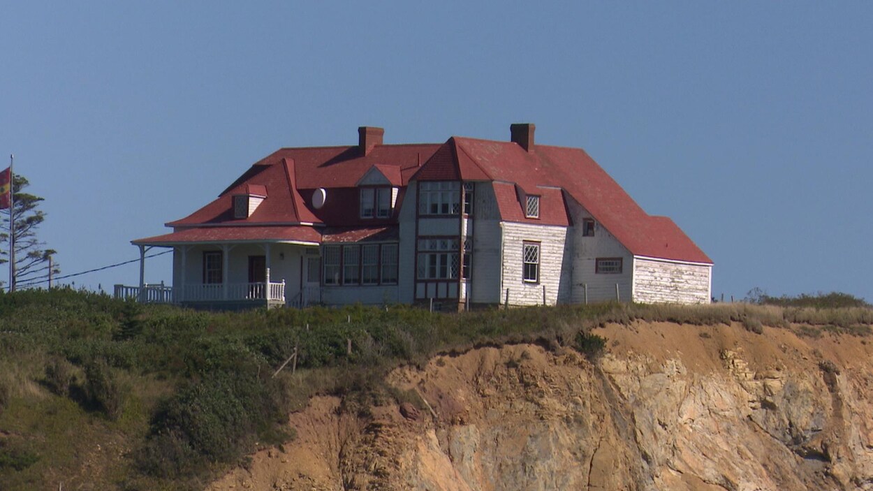 La villa, dont la peinture est défraîchie, est maintenant très près de la falaise.