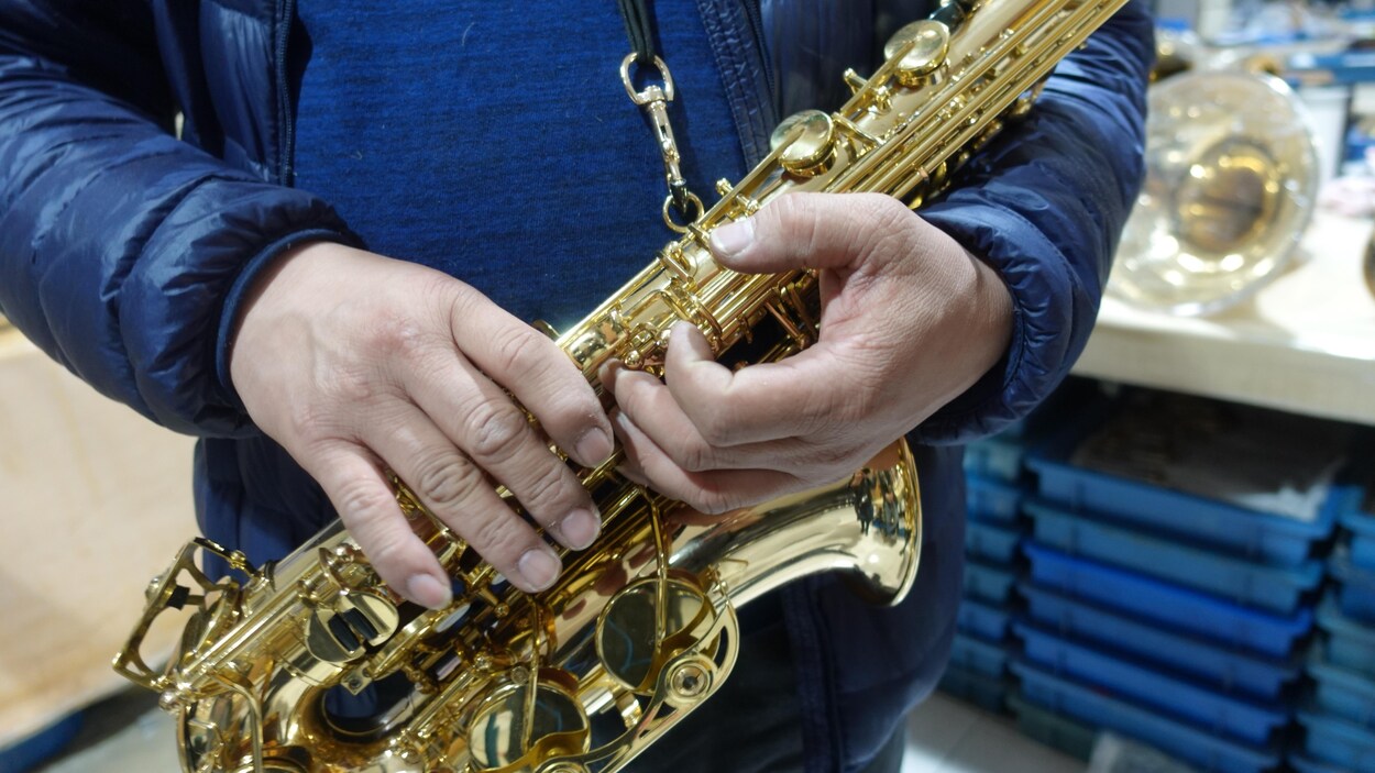 Un homme sert contre lui un saxophone.