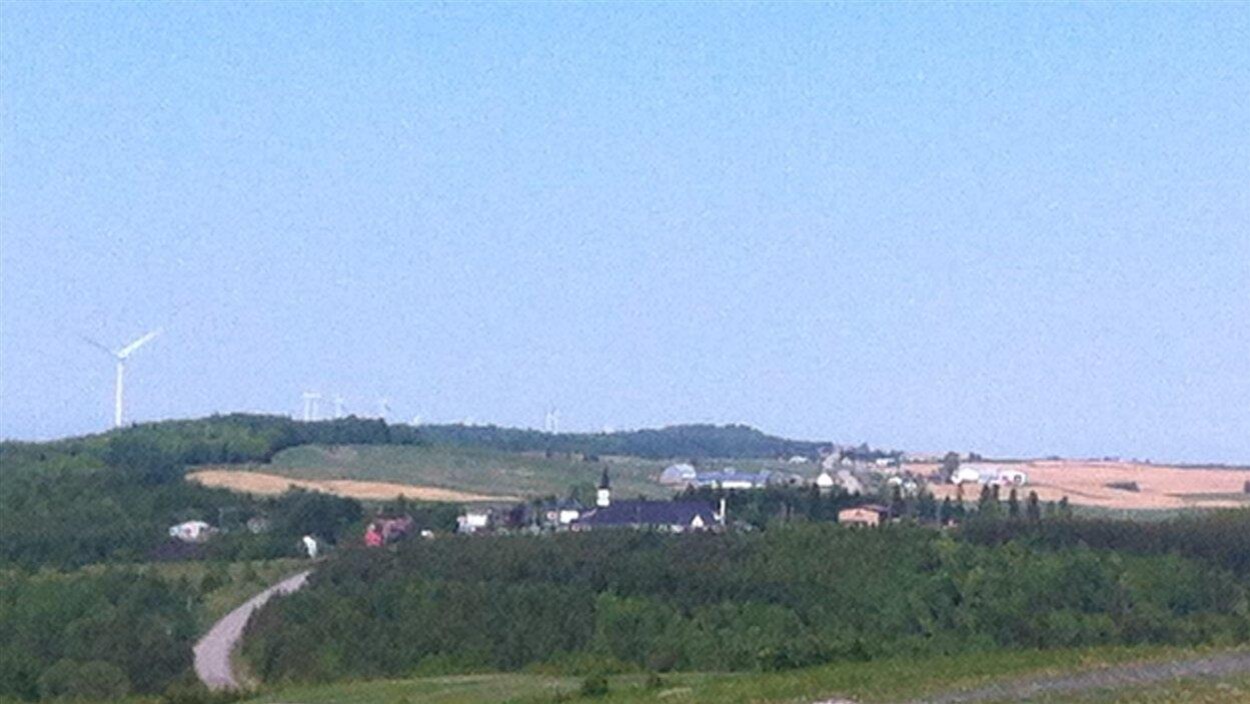 Le village de Saint-Léandre est bordé, d'un côté, d'une série de tours d'éoliennes, et de champs, de l'autre.