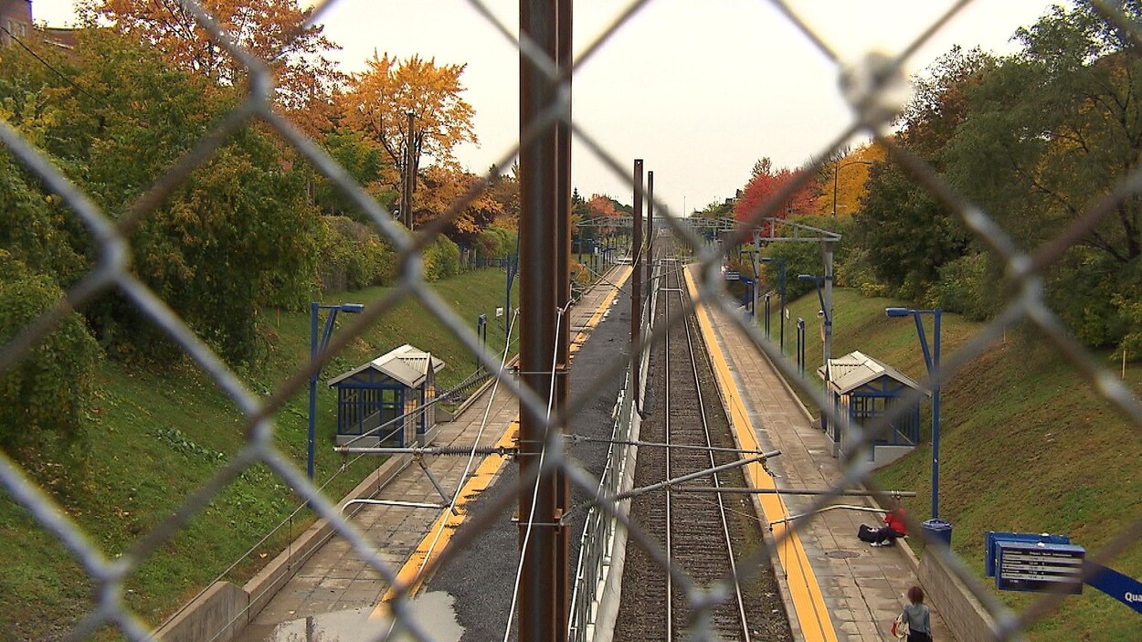Le rail vu à travers le grillage d'une clôture.