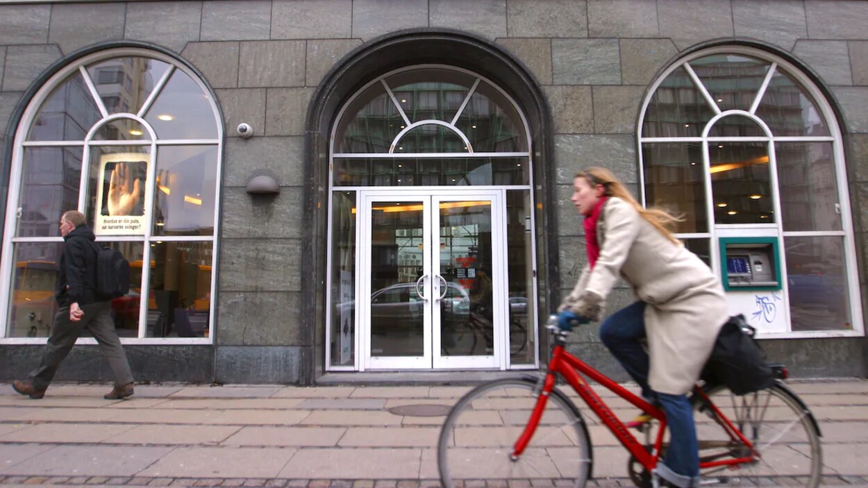 Une dame sur un vélo devant un édifice.