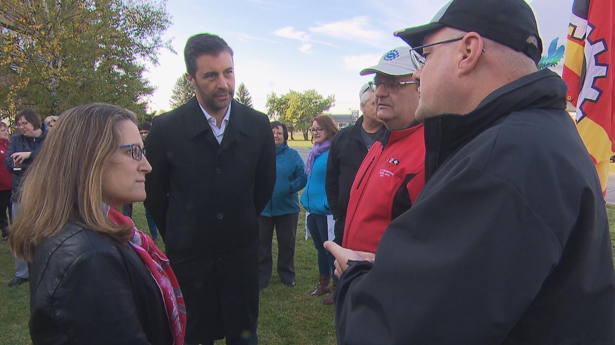 Chrystia Freeland et Vincent Garneau discutent avec deux hommes à l'extérieur.