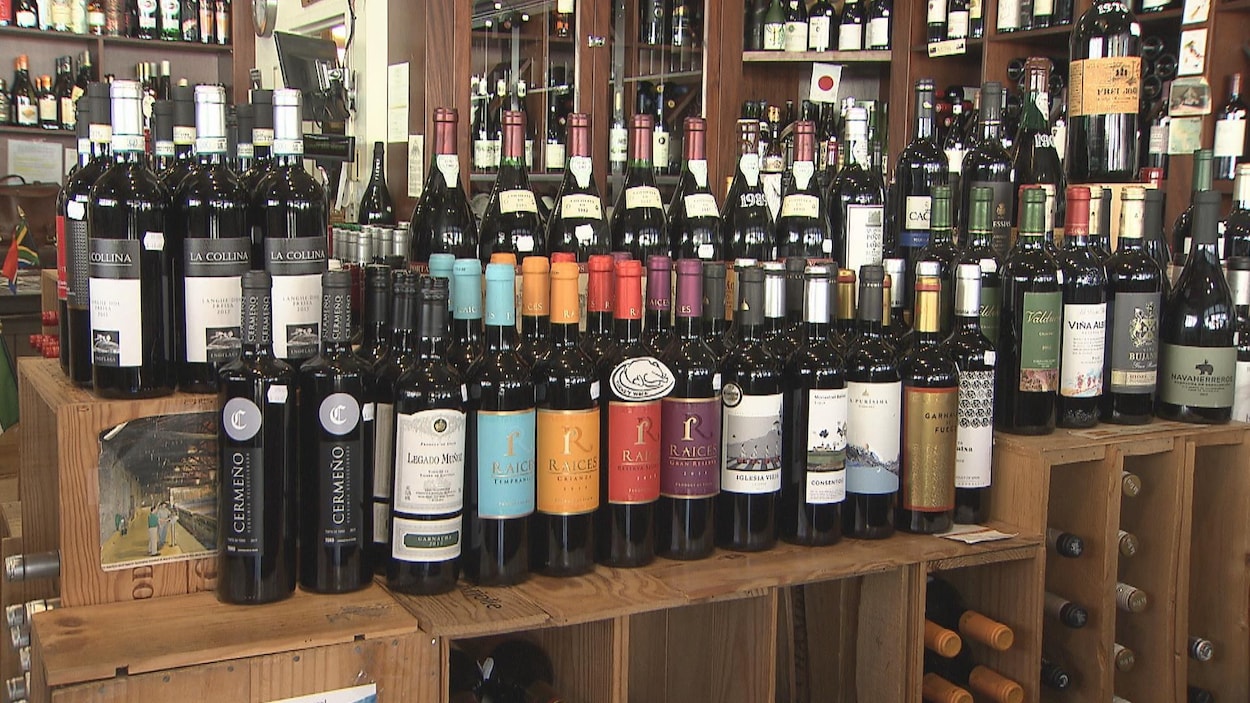 Des bouteilles de vin sur un présentoir et sur des étagères dans une boutique.