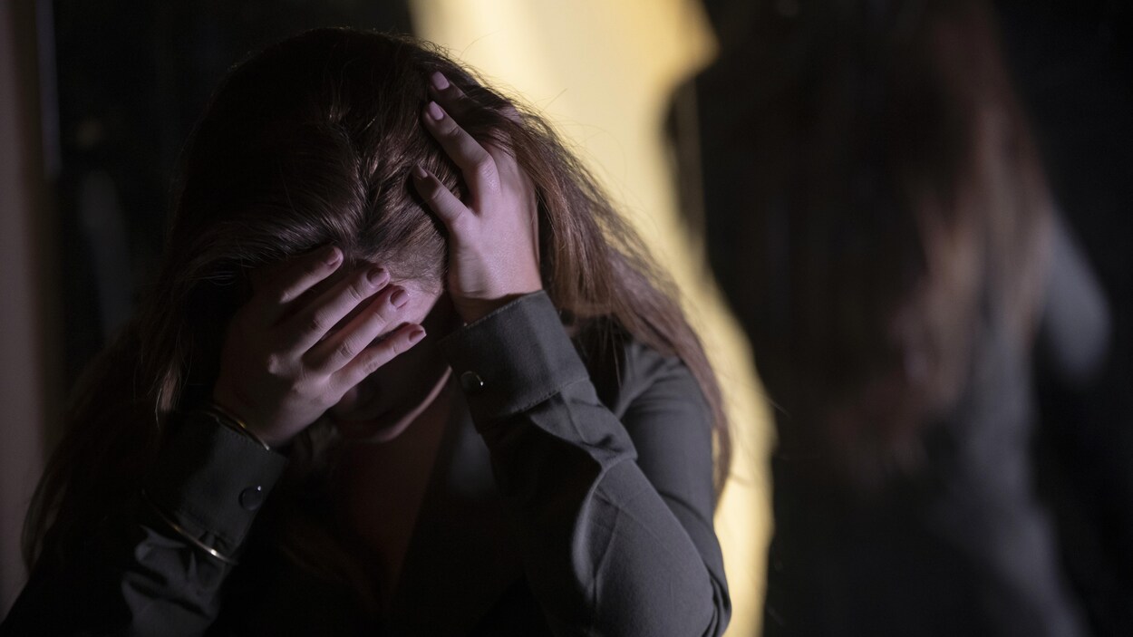Une femme, le visage caché dans ses mains