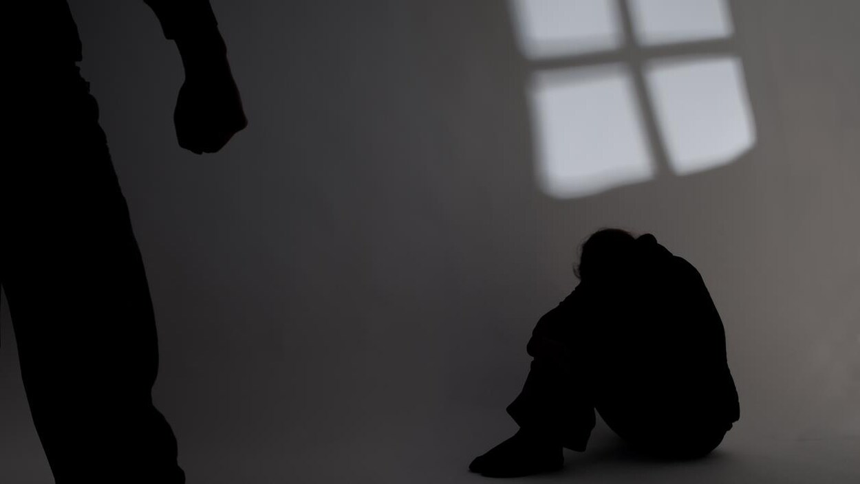 Une personne est assise par terre et une autre personne au premier plan a le poing serré.