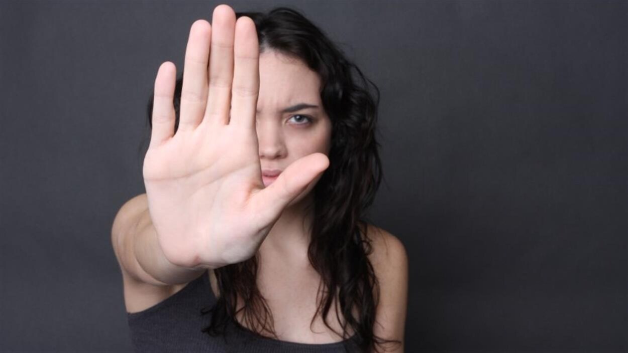 Une femme dresse sa main devant son visage.