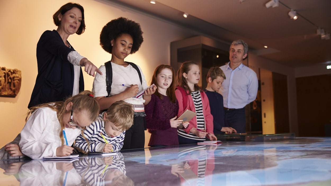 Des enfants en visite au musée regardent une carte.