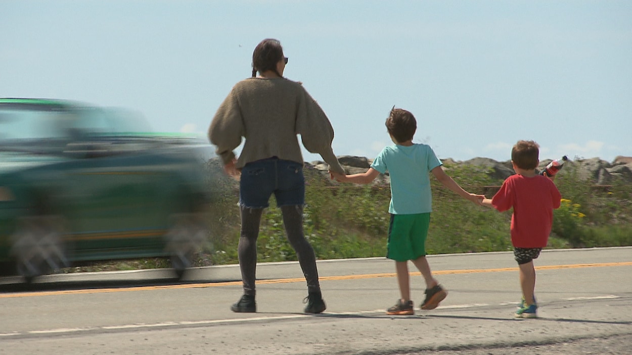 Une mère et ses enfants tentent de traverser la route.