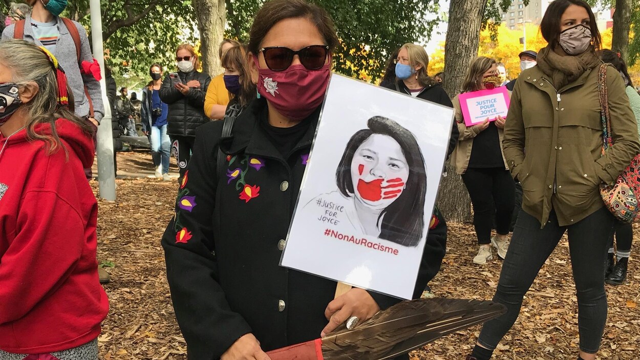 Une femme innue masquée porte une pancarte de Joyce Echaquan.