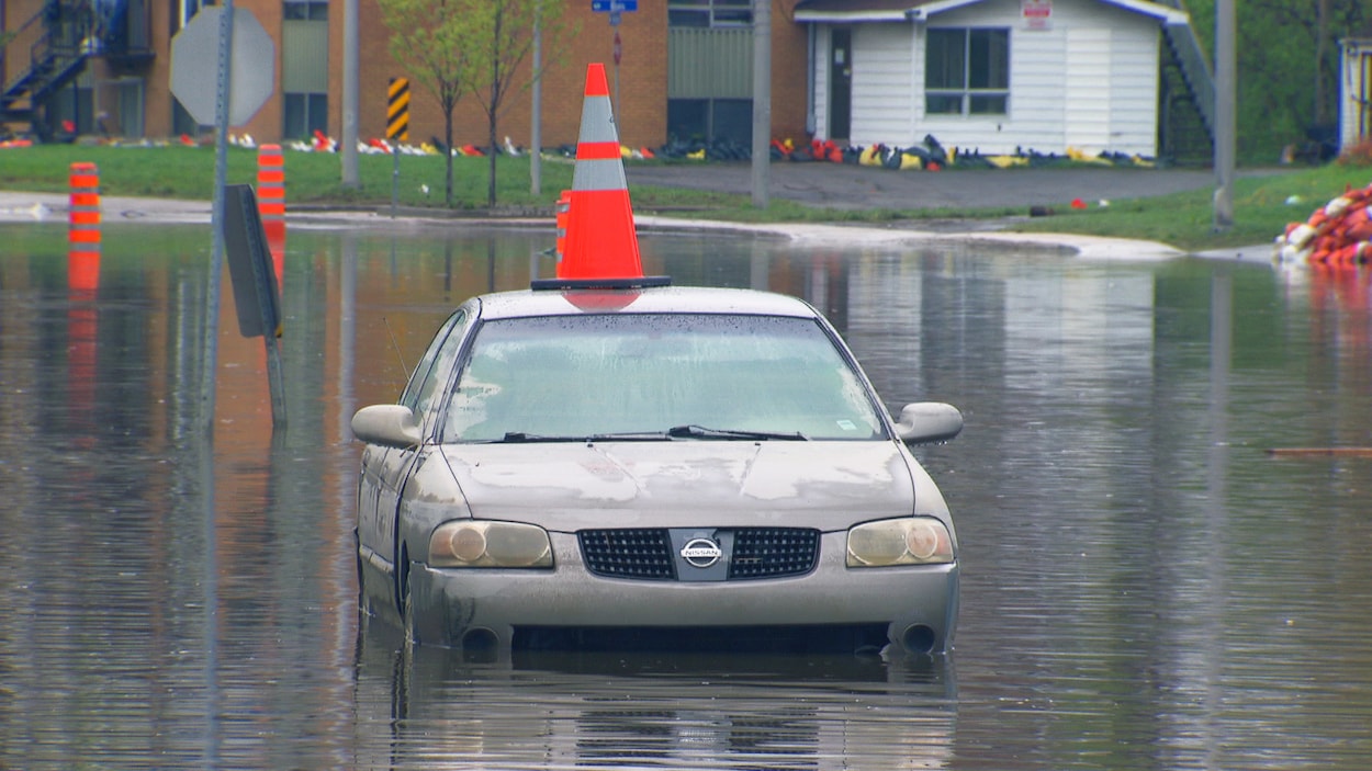 Une voiture inondée avec un cône orange sur le toit. Une voiture inondée avec un cône orange sur le toit.
