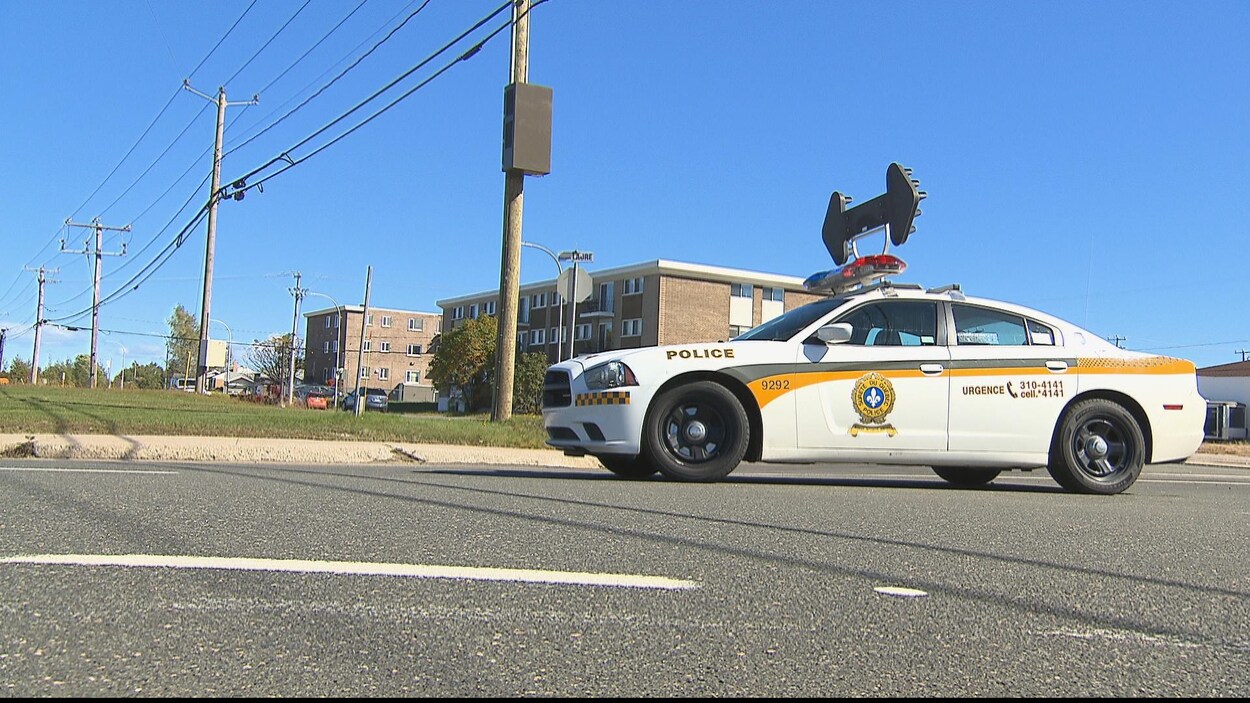 Voiture de police sur laquelle est installée de l'équipement de signalisation, une flèche à double sens, stationnée dans une rue de Sept-Îles.