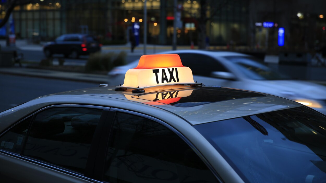 Le haut d'un taxi dans une rue de Toronto. Le signe taxi est illuminé.