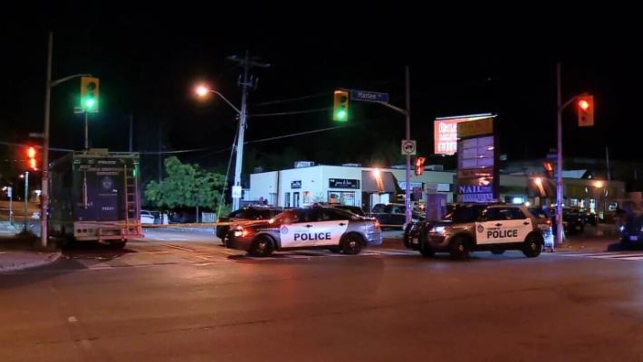 Des voitures de patrouille de police bloquent l'accès à une rue en plein milieu de la nuit dans le quartier nord-est de Toronto, North York. Les feux de circulation sont verts. Il y a aussi une banderole de sécurité jaune pour bloquer l'accès à cette intersection de rues.