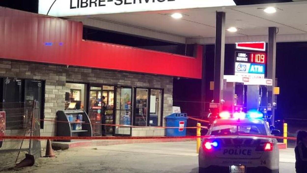 Un voiture de police devant une station service.