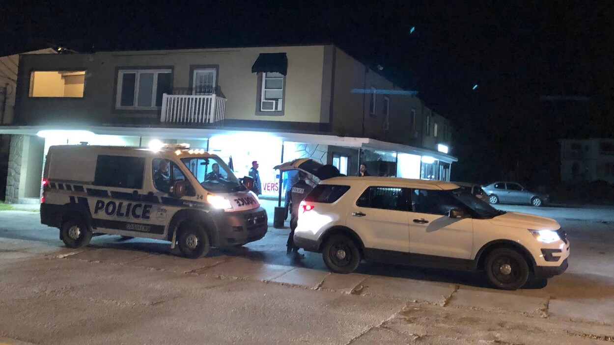 Des voitures de police stationnées devant un commerce.