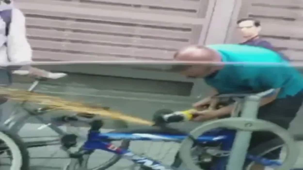 Des étincelles se dégagent d'un cadenas qu'un homme est en train de scier avec une meuleuse.