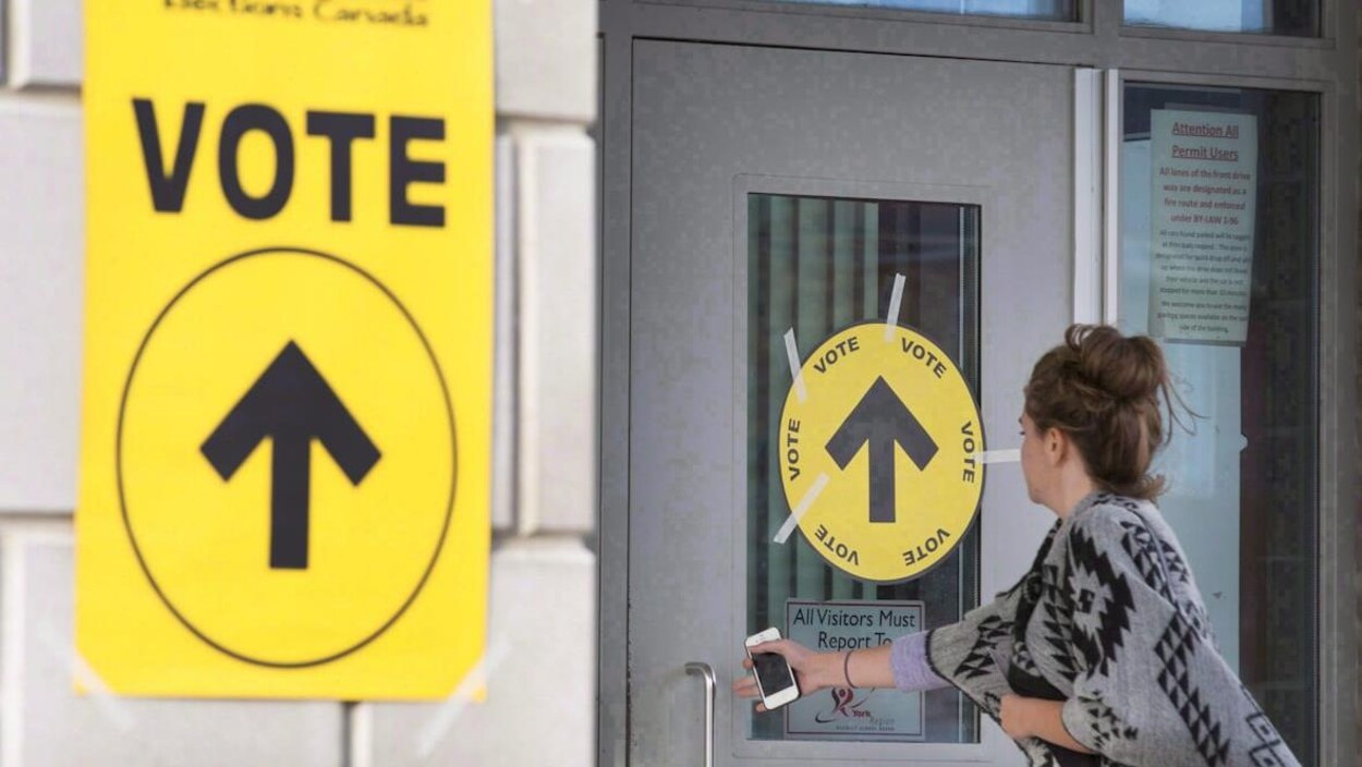 Une femme entre dans un bureau de vote.
