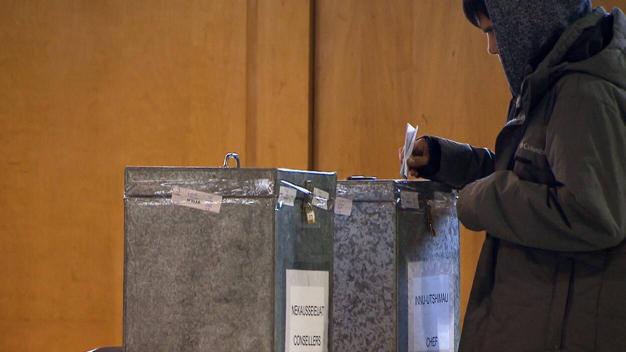 Un homme dépose son bulletin de vote dans une boîte de scrutin.