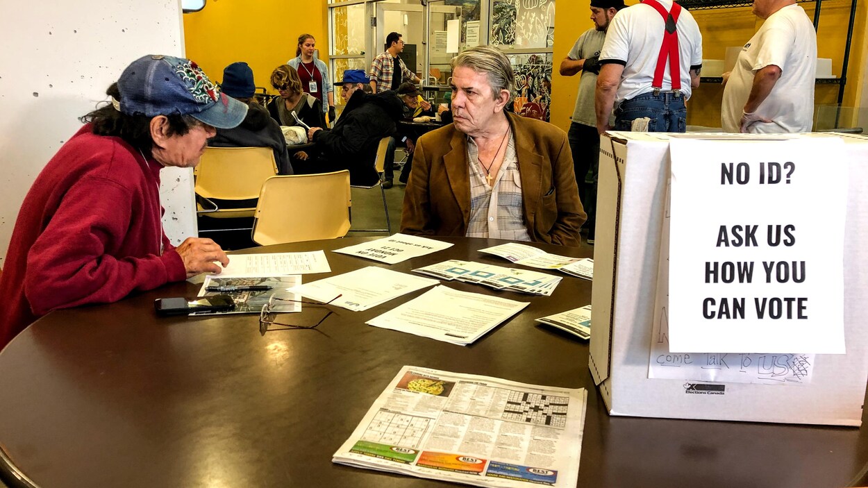 Michael Nardachioni et Edwian Canfield sont assis à une table et discutent, derrière eux, des personnes dînent au repas offert par l'Union Gospel Mission.